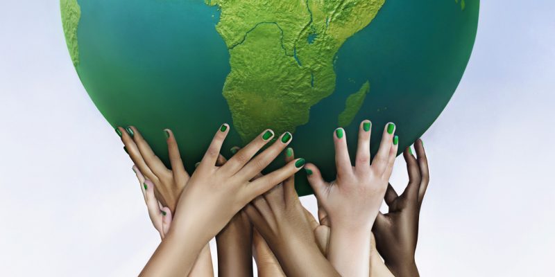 Multiracial hands holding green globe